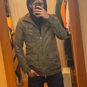 Field Jacket från J.Lindeberg  - Säljer en olive grön Field Jacket i storleken XS men skulle säga att den passar mer S. Det finns några få defekter som ni kan se på bild 4&5. Passar perfekt till dig som vill ha en snygg jacka inför hösten. Hör av dig vid minsta fundering!! 