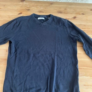 Mörkblå v-ringad tröja Jack & Jones - En svart v-ringad tröja från Jack & Jones i klassisk stil. Tröjan har långa ärmar och ribbade muddar vid hals, ärmslut och nederkant. Perfekt för dig som gillar en enkel och stilren look. Ingen fläck eller något hål.