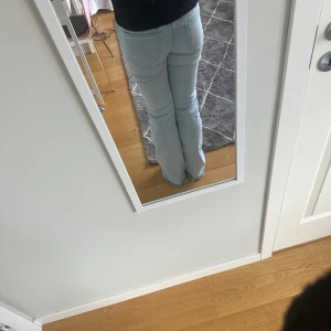 Ljusblå bootcut jeans från H&M Divided - Säljer ett par ljusblå bootcut jeans från H&M Divided i storlek 36. Jeansen har klassisk femficksdesign, normal passform upptill och utsvängda ben. Materialet är mjukt denim i bomull med lite stretch för extra komfort. Perfekt för dig som gillar retrovibbar och snygg siluett.