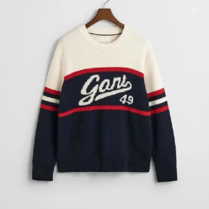 GANT stickad tröja navy/vit röd  - Snygg stickad tröja från GANT i navyblått och vitt med röda detaljer. Stor Gant-logga och siffran 49 framtill, samt randiga ärmar. Rund halsringning och ribbade muddar. 
