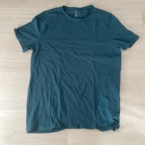 Blå basic t-shirt i bomull - En enkel blå t-shirt från H&M med rund hals och korta ärmar. Modellen är normal passform och materialet är mjuk bomull, perfekt för chill dagar. Färgen är djup blå och t-shirten har en clean look utan mönster eller detaljer.