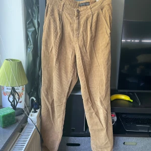 Beiga manchesterbyxor från Dilvin - Snygga beiga manchesterbyxor från Dilvin i storlek 38. Byxorna har klassisk passform med raka ben, sidofickor och hällor för bälte. Perfekta för dig som gillar retrovibbar och mjukt material. Styla med sneakers eller boots för en chill look.