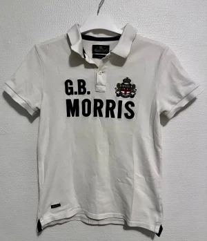 Vit piké från Morris Gents, S - Vit pikétröja från Morris Gents ett broderat emblem på bröstet. Pikén är gjorde av 100% bomul och modellen har en normal passform. Snygg och stilren. Perfekt för dig som gillar att vara lite stiligare i vardagen