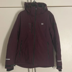Skid jacka - Skidjacka ifrån lager 157, köptes säsongen 2023 och användes 2-3 gånger. Jackan funktioner: Avtagbar huva, kan även reglera storleken spänna åt mm, bröst ficka samt ficka på vardera sida av framsida, hög krage, insidan av jackan kan du knäppa åt.