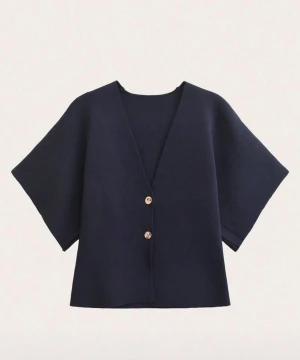 Mörkblå kofta med korta ärmar - Snygg mörkblå kofta med v-ringning och två knappar framtill. Modellen är loose fit och har korta, vida ärmar som ger en chill och modern vibe. Perfekt att slänga på över en t-shirt eller linne för en enkel men stilren look.