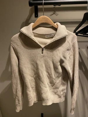 stickad half zip-tröja från brothers - Säljer en beige stickad tröja från Brothers i storlek S. Tröjan har ribbad struktur, hög krage och half zip-dragkedja framtill. Perfekt för lager-på-lager och chill stil. Långärmad och i mjukt material som håller dig varm under kyliga dagar. Näsan aldrig andvänd då den är för liten 