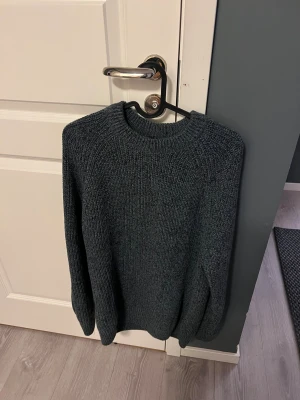 Mörkgrå stickad tröja unisex - Snygg mörkgrå stickad tröja med rund hals och långärmad modell. Perfekt för dig som gillar en enkel och klassisk look med lite loose passform. Materialet är mjukt och värmande, passar dig som vill ha en chill och stilren vibe.