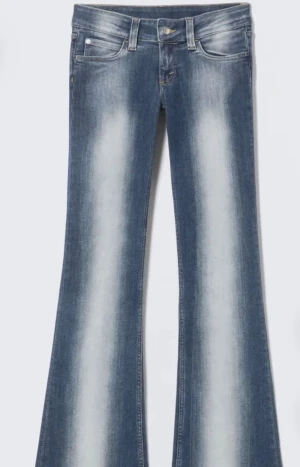 Weekday jeans 💖💖 - Snygga blå bootcut jeans med tydliga ljusa slitningar längs benen. Klassisk femficksmodell med dragkedja och knapp. Jeansen har låg midja och är tillverkade i mjukt denimtyg som sitter skönt. Perfekta för dig som gillar retrovibbar och markerade ben. I storlek 23/30. De är uppsydda men som man kan se är de super lätt o bara sprätta upp de annars om man vill.💖💖