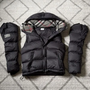 Burberry jacka/väst  - Snygg svart jacka/dunväst från Burberry med avtagbara ärmar. Västen har dragkedja, tryckknappar och två fickor framtill. Storlek-S. Fraktar spårbart! Perfekt för vintern.