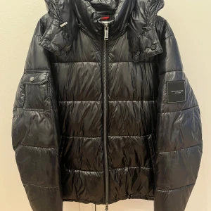 Svart pufferjacka Michael Kors L - Svart pufferjacka från Michael Kors i storlek L (Herr). Jackan är i väldigt bra skick utan några skador. Köpt på Michael Kors hemsida
