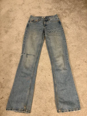 Ljusblå jeans - Ljusblå jeans med klassisk femficksdesign och slitna detaljer på låret och knät. Jeansen har lite utsvängd passform och är tillverkade i tåligt denimtyg. Perfekta för en avslappnad och trendig look.