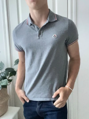 Moncler pike  - En av monclers klassiker, grå Moncler pike / pique med många fina detaljer omkring tröjan  riktigt bra skick och passar perfekt på modellen som är 180 cm 75 kg och bär storlek M. Såklart äkta, köpt av store endas tidigare ägare! 
