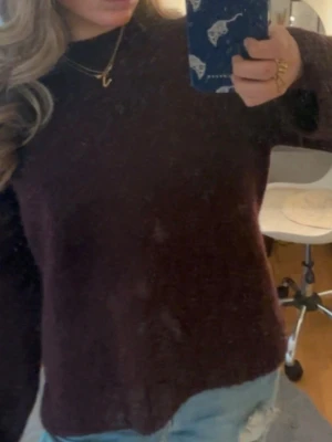 Vinröd stickad tröja - Mysig vinröd stickad tröja med enkel design och rund hals. Tröjan har lång ärm och en loose passform som gör den perfekt att slänga på sig till jeans. Perfekt för kyligare dagar. Inte alls nopprig 