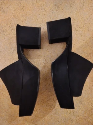 Svarta plattformssandaler från NLY Shoes - Säljer ett par svarta sandaler från NLY Shoes med chunky plattform och bred klack. Skorna har öppen tå och bred rem över foten, tillverkade i mocka-look. Storlek 38, använda en gång. Hämta/lämna helst i Stockholm city/Solna.