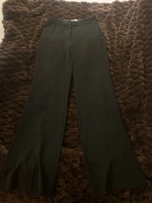 Svarta kostymbyxor från Ottod'Ame - Snygga svarta kostymbyxor från Ottod'Ame med raka ben och diskret midja. Byxorna har klassisk passform och är tillverkade i ett mjukt material som känns skönt mot huden. Perfekta till en stilren look och har fickor på sidorna.