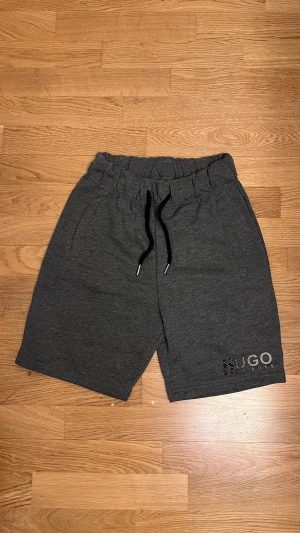 Mörkgrå shorts i storlek S - Snygga mörkgrå shorts.  Tillverkade i mjuk bomullsmix och har diskret logga på ena benet. Perfekta för chill dagar eller träning.