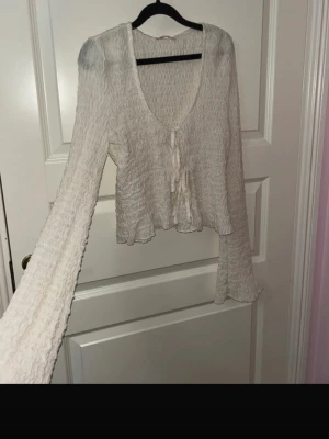 Vit blus med volanger  - Vit blus med knytning i mitten och trumpet / vida ärmar 