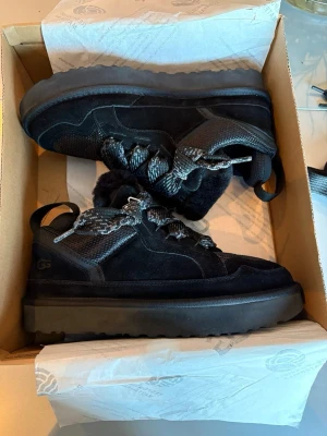 Svarta UGG lowmells storlek 45 - Säljer ett par svarta UGG boots med chunky sula och breda snören. Storlek 45 men passar 44. De på bilderna medföljer. Aldrig använda