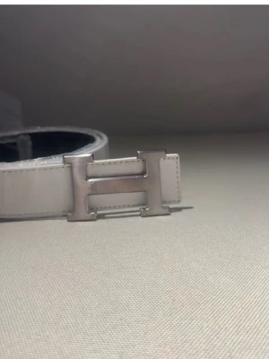 Fint H-bälte⚪️🩶 - Bilderna visar ett vitt bälte med ett stort H-format spänne i silver, men ingen väst syns på bilderna. Size 110! Pris kan diskuteras 