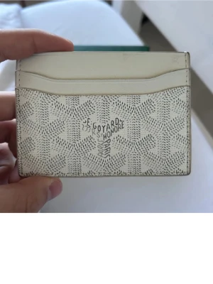 Beige kortfodral - Säljer ett stilrent beige kortfodral frånmed ikoniskt mönster och flera kortfack. Perfekt för dig som vill ha ett smidigt och snyggt sätt att bära dina kort. Klassisk design med framtill.