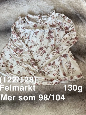 Blommig långärmad blus från Newbie  - Säljer en söt blommig blus från Newbie. Blusen har volangdetaljer vid halsen och axlarna samt långärmad passform. Perfekt för vår och sommar. 🌸 Fläckar. Står 122/128 men måste vara felmärkt då den är lika stor som tröjorna i 98/104. 