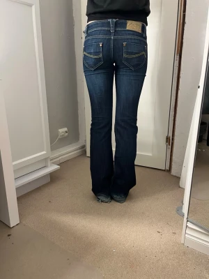 Mörkblå bootcut jeans lågmidjade - SJUKT SNYGGA JEANS som är alldeles för långa för mig från vintage bershka! Superlågmidjade mörkblå bookmtcut jeans! Sluta vid hälsen annars superbra skick! Midjemått:38cm, innerbenslängd: 81cm