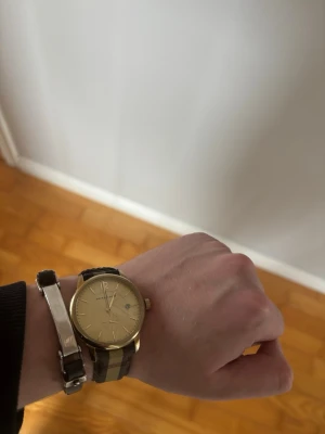 Silver och läder armband  - Ett stilrent och exklusivt armband med svart band i elegant kontrast mot polerade metalldetaljer. En minimalistisk design som utstrålar modern lyx och tidlös kvalitet – perfekt för en sofistikerad look