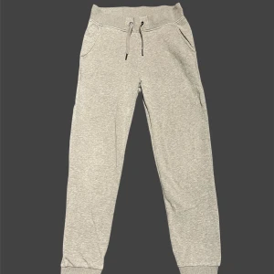 Grå mjukisbyxor från Peak Performance - Snygga ljusgrå mjukisbyxor från Peak Performance med ribbade muddar, snörning i midjan och två sidofickor. Perfekta för chill eller träning, tillverkade i mjuk bomullsblandning för maximal komfort.