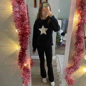 Mörkblå stickad tröja med paljettstjärna - Mysig mörkblå stickad tröja från Gina Tricot med en stor silverfärgad paljettstjärna på bröstet. Tröjan har rund hals, lång ärm och en loose passform som är perfekt för chill dagar. Ribbstickade muddar vid hals och ärmslut. Snygg och unik detalj framtill!