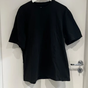 Svart oversized t-shirt i bomull - Enkel svart t-shirt i oversized modell med rund hals och korta ärmar. Tillverkad i mjuk bomull, perfekt för en clean och avslappnad stil.