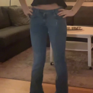 Blå bootcut jeans från Zara - Snygga blå jeans från Zara med klassisk femficksdesign och bootcut-ben. Jeansen har normal passform, dragkedja och knapp framtill samt bälteshällor. Tillverkade i jeansmaterial med en lätt tvättad look som ger en cool vibe.