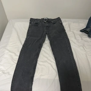 Svarta slim jeans från 157, W29 L32 - Svarta jeans från 157 med slim fit och klassisk femficksdesign. Jeansen har en snygg tvättad look och raka ben, perfekt för dig som gillar en smalare passform. Materialet är jeans och midjan är normal. Märkt med 'SLIMMY' på insidan.