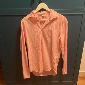 Rosa skjorta från Stenströms, M - Snygg rosa skjorta från Stenströms i fitted body-modell. Skjortan har klassisk krage, långa ärmar och knäppning framtill. Perfekt för dig som gillar stilrena och färgglada plagg. Tillverkad i mjuk bomull för en skön känsla. Nypris 1500kr, hos mig för mindre än halva. Använd en gång, storlek M