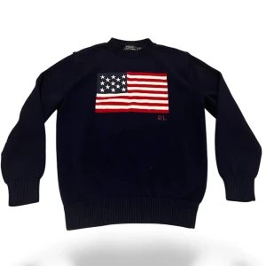 Mörkblå stickad tröja Polo Ralph Lauren - Snygg mörkblå stickad tröja från Polo Ralph Lauren med amerikansk flagga broderad på bröstet och RL-detalj. Tröjan har rund hals, ribbade muddar och långärmad passform. Perfekt för dig som gillar klassisk stil med en twist.