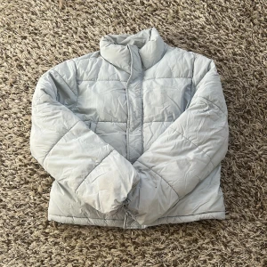 Ljusblå pufferjacka från Gina Tricot - Säljer en ljusblå pufferjacka från Gina Tricot i storlek 158/164. Jackan har mellanhög krage, två sidofickor och clean look. Stängs med dragkedja och knappar framtill. Perfekt för kalla dagar med sin fluffiga och mjuka känsla💗