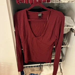 Vinröd långärmad topp från Gina Tricot - Säljer en vinröd långärmad topp från Gina Tricot med djup v-ringning. Aldrig använd 
