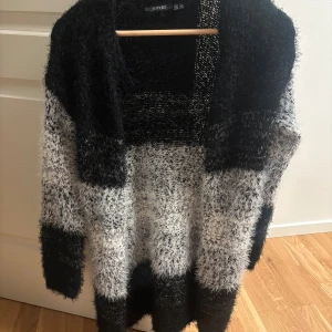 Randig fluffig kofta från Esmara - Mysig och oversized kofta från Esmara i svart och vit med breda ränder. Tröjan är fluffig och stickad, har lång ärm och öppen front utan knappar. Perfekt för att chilla hemma eller när du vill ha en extra varm lager på hösten.