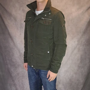 Bailey Field jacket - J-lindeberg - Stl S - | Snygg och eftertraktad field jacket från J-Lindeberg I olivgrön färg | Nytt skick: 9,5/10, inga defekter | Modellen på bilden är 175cm lång | 