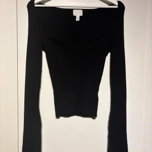Svart ribbad långärmad topp H&M - Säljer en svart ribbad långärmad topp från H&M med snygg v-ringad hals och figurnära passform. Kommer tyvärr aldrig till användning 