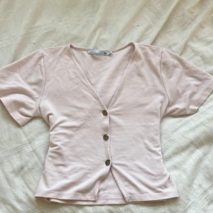 Ljusrosa kortärmad blus från 157 - Supersöt ljusrosa blus från 157 med v-ringning och knappar framtill. Storlek M men passar även dig som har S-XS. 💕