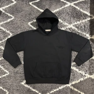 Svart Essentials hoodie - Svart hoodie från Essentials Fear of God med stor logga på ryggen och mindre logga på bröstet. Klassisk känguruficka framtill, ribbade muddar och huva. Jag är 180cm, 68kg och den sitter bra på mig. Pris kan diskuteras vid snabb affär.