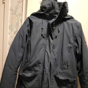 Mörkblå vinterjacka  - Vinterjacka från Henri Lloyd i mörkblå färg, storlek L. Jackan har huva, snörning vid halsen, flera fickor med både dragkedja och knappar.  Använd två gånger. 