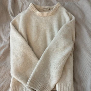 Beige stickad tröja från Gina Tricot - Mysig beige stickad tröja från Gina Tricot med rund halsringning och ribbade muddar. Perfekt för lager-på-lager och chill höst- eller vinterstil. Enkel och stilren design som passar till allt.