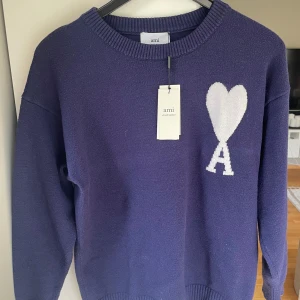 Mörkblå stickad tröja från Ami Paris  - Säljer nu min mörkblå stickad tröja från Ami Alexandre Mattiussi, testad men aldrig använd| Den har ett vit hjärtlogga och bokstaven A på bröstet. Tröjan har en rund halsring, ribbade muddar och lång ärm. Perfekt för dig som gillar stilrena till höst och vinter🍁❄️| Passar mellan 177-185cm lång| tveka inte på att skriva vid frågor elle prisförslag| 