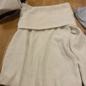 Vit ribbad stickad kjol - Mysig vit stickad kjol med ribbad struktur och bred, vikt midja. Kjolen har en mjuk och skön känsla, perfekt för kyligare dagar. Passformen är normal och modellen är något längre, vilket ger en avslappnad men ändå stilren look.