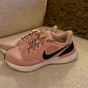 Nike sneakers  - Snygga rosa Nike sneakers med svart swoosh på sidan och vit sula. Skorna har mesh-ovandel för bra ventilation och klassisk snörning. Perfekt för dig som gillar sportig stil och vill ha bekväma skor till vardags. Låg modell med rund tå och platt sula.