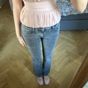 Grå lågmidjade bootcut jeans med tvättad look - Super snygga gråa lågmidjade jeans! Från ginatricot, har en ”missfärgning” men var så när jag köpte de så vet ej om de ska vara så eller inte💓💓💓