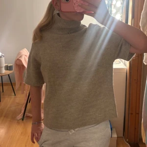 Beige polotröja från ginatricot  - Säljer en beige polotröja med korta ärmar. Tröjan har en loose passform och är stickad material. 