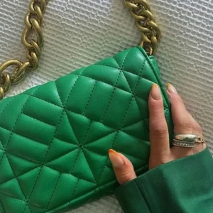 Grön quiltad axelväska från Zara - Snygg grön axelväska från Zara med quiltad design och grov guldfärgad kedja som axelrem. Väskan är tillverkad i skinnimitation och har ett coolt geometriskt mönster. Perfekt storlek för det viktigaste och ger en trendig touch till din outfit.