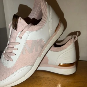 Michael Kors sneakers i rosa och vitt - Helt nya Snygga sneakers från Michael Kors i ljusrosa och vitt med guldiga detaljer vid hälen. Skorna har stickad textil upptill, skinnimitation på sidorna och tydlig MK-logga. Perfekta för dig som vill ha en sportig men ändå trendig look.- kan gå ner i pris vid snabb affär  - Finns i Göteborg  - Kan även fraktas